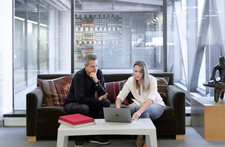 two people on a couch looking at a computer and negotiating