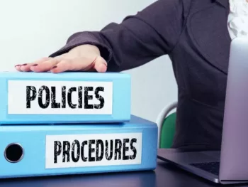 a person with their hand on a few binders that says policies and procedures