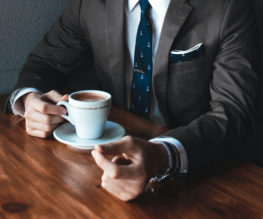 a person in a business suit with a cup of coffee